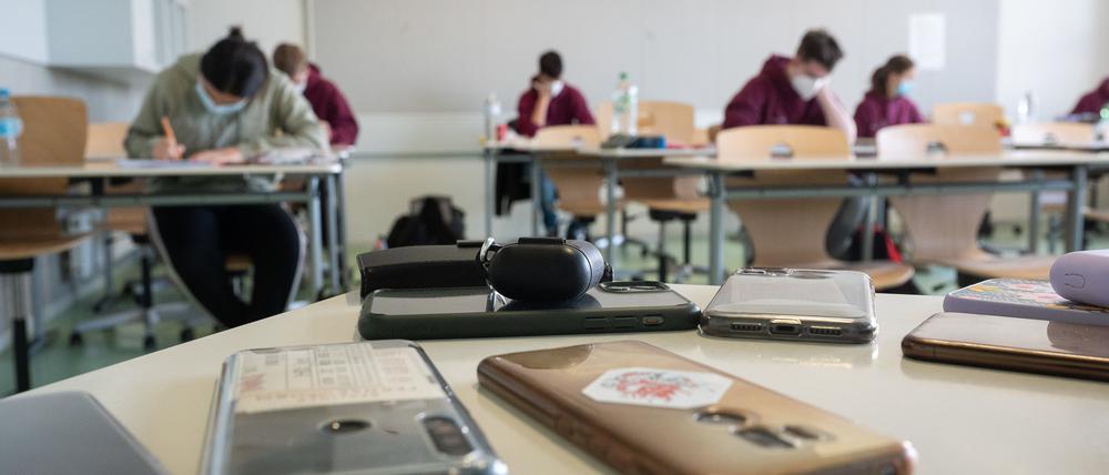 Ausgeschaltete Smartphones liegen am ersten Tag der Abiturprüfungen an der Prälat-Diehl-Schule in einem Klassenzimmer (Symbolbild).
