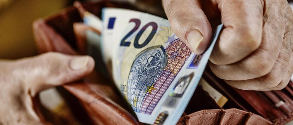Eine Seniorin zieht einen 20 Euro Schein aus ihrem Portemonnaie. 