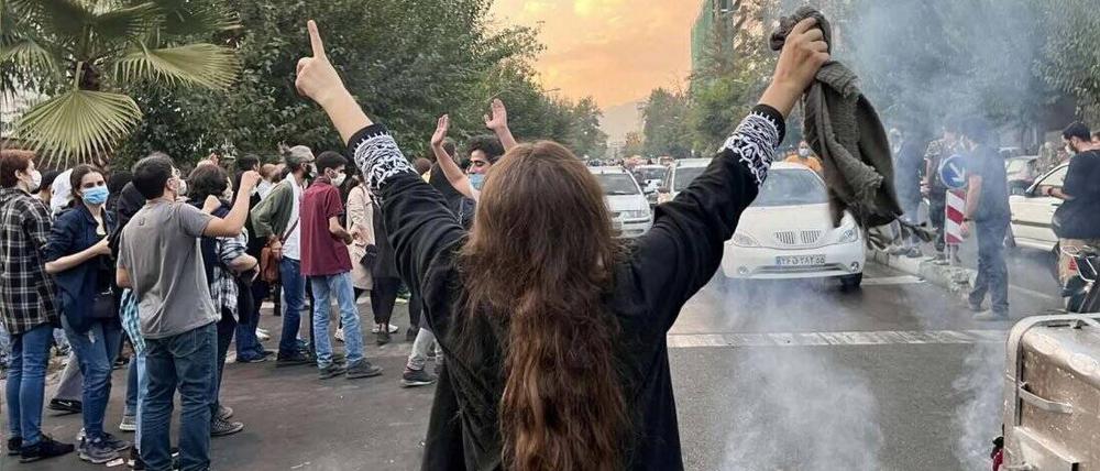 Eine Frau steht inmitten der Proteste in Teheran