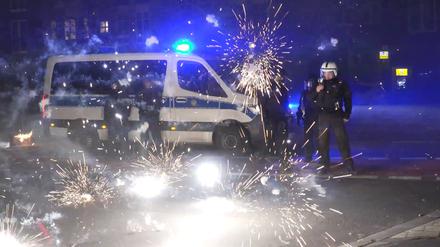 Berliner Polizeibeamte stehen hinter explodierendem Feuerwerk. 