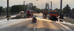 Hier der Blick von der gesperrten Fahrbahn - hinten links pumpt die Feuerwehr mit einem Schlauch das Wasser in die Havel.