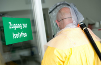 Ein Mann in Schutzausrüstung betritt bei einem Pressetermin eine Sonderisolierstation in einem Münchner Klinikum. Foto: picture alliance / dpa