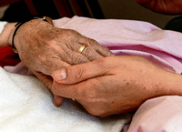 Eine Hospiz-Schwester hält die Hand einer todkranken Bewohnerin. Foto: dpa