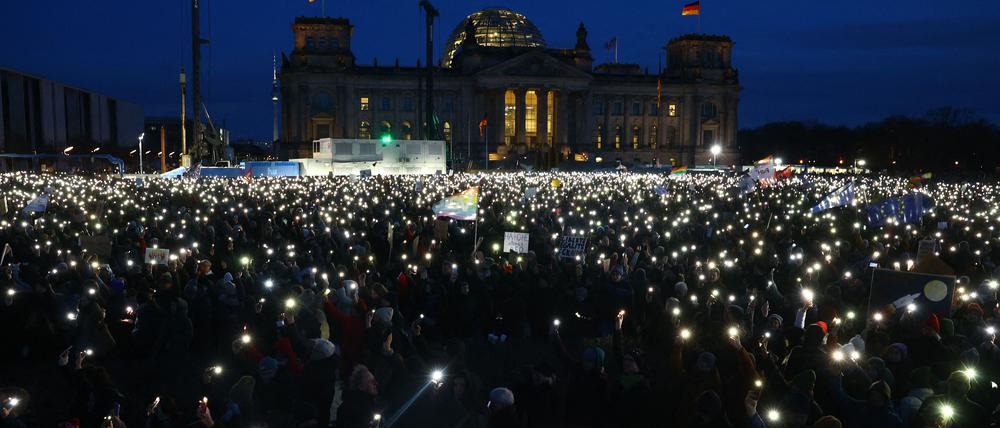 Teilnehmer leuchten mit ihren Handys während einer Demonstration gegen Rassismus und rechtsextreme Politik vor dem Reichstagsgebäude in Berlin.