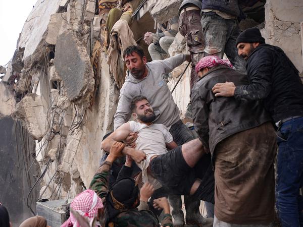 Der erste Tag nach den Erdbeben: Einwohner bergen einen verletzten Mann aus den Trümmern eines eingestürzten Gebäudes in der von Rebellen kontrollierten kurdischen Stadt Afrîn.