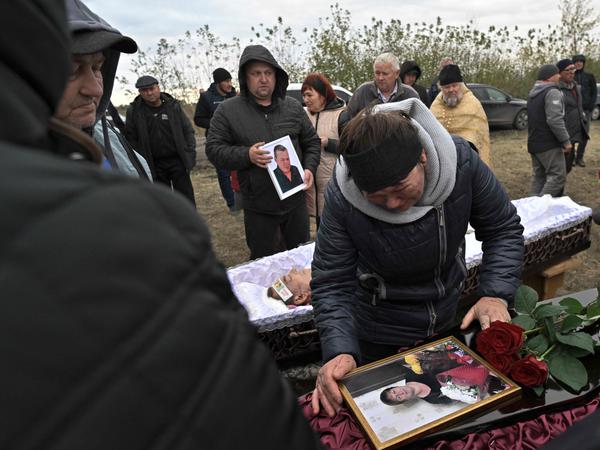 Angehörige und Freunde trauern nach einem russischen Luftangriff im ostukrainischen Dorf Goza. 