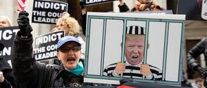 Archivbild: Demonstranten in New York halten Schilder mit einem Bild von Donald Trump im Gefängnis und Schildern mit der Aufschrift „Anklage gegen die Verantwortlichen des Gerichts“ in die Höhe.