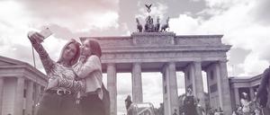 Die meisten Selfies werden Statistiken zufolge im Urlaub gemacht, hier Touristinnen am Checkpoint Charlie in Berlin.