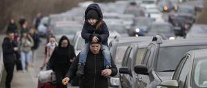 Flüchtlinge gehen an Fahrzeugen vorüber, die vor dem Grenzübergang von der Ukraine nach Moldawien warten.