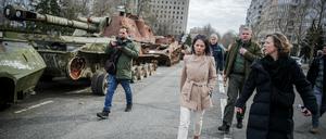 Annalena Baerbock geht bei ihrem Besuch des ehemaligen Sitz der Regionalverwaltung der Oblast Mykolajiw an zerstörten russischen Panzern vorbei. 