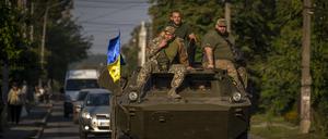Soldaten der ukrainischen Armee sitzen auf einem gepanzerten Militärfahrzeug.