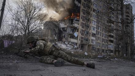 Ein ukrainischer Polizist in Awdijiwka, der vor einem brennenden Gebäude in Deckung geht.