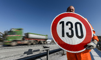 Ein Straßenwärter hält an der Autobahn A81 ein Schild mit der Aufschrift "130" in den Händen. Foto: Patrick Seeger / picture alliance / Patrick Seege
