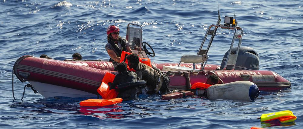 Ein Mitglied der spanischen Nichtregierungsorganisation Open Arms hilft Migranten, an Bord zu kommen, nachdem ihr Holzboot während einer Rettungsaktion südlich der italienischen Insel Lampedusa im Mittelmeer gekentert war. 