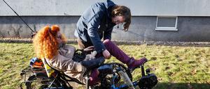 Start zur Radtour: Ihr Assistent hilft ihr auf das Dreirad mit elektrischer Tretunterstützung.