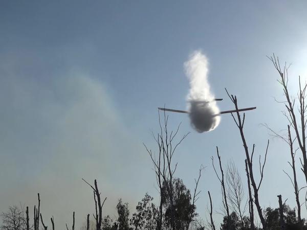 Ein kleines Löschflugzeug wirft Wasser ab über einem Waldbrand in einem munitionsbelasteten Gebiet bei Jüterbog. 