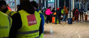 Eine Gruppe mit Rollkoffern geht während eines Warnstreiks am frühen Morgen am Flughafen Berlin-Brandenburg BER an Streikenden vorbei. Die Gewerkschaft Verdi hat am 25. Januar 2023 zu einem ganztägigen Warnstreik am Flughafen Berlin-Brandenburg aufgerufen.