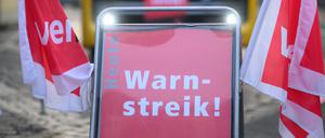 Ein Schild „Warnstreik“ steht vor einem Bus der Dresdner Verkehrsbetriebe.