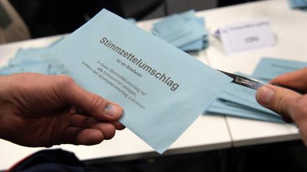 Ein Wahlhelfer öffnet im City Cube nach der wiederholten Wahl den Stimmzettelumschlag eines Briefwählers.