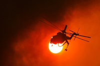 Ein Feuerwehrhubschrauber fliegt in Griechenland vor der Sonne zu einem Waldbrand. Foto: REUTERS / Alkis Konstantinidis