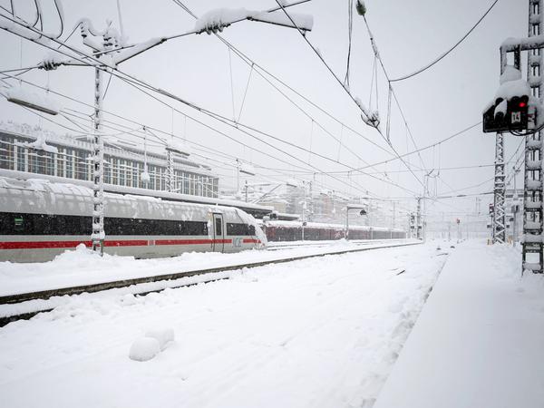 Ein ICE steht neben einem verschneiten Gleis und Bahnsteig am Münchener Hauptbahnhof. Der Zugverkehr von und zum Hauptbahnhof wurde wegen der Schneemengen vorübergehend eingestellt. 