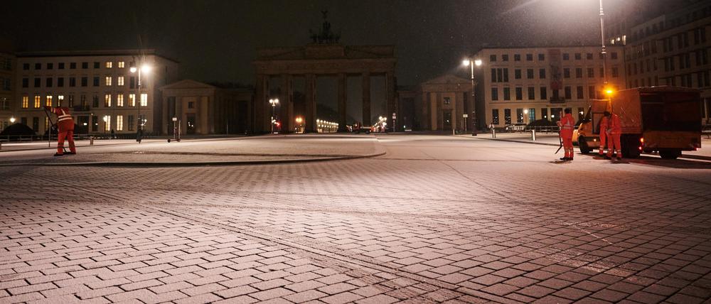 Mitarbeiter der Stadtreinigung BSR arbeiten am Montagmorgen bei Schnee vor dem Brandenburger Tor.