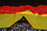 Fußballfans unter einen überdimensionalen Deutschlandflagge bei einem WM-Qualifikationsspiel in Nürnberg. Foto: Peter Kneffel/dpa