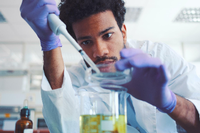 Ein junger Wissenschaftler hantiert im Labor mit Pipette und Petrischale. Foto: Getty Images/iStockphoto