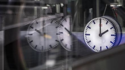 Die Uhr auf einem Gleis im Berliner Hauptbahnhof zeigt 2 Uhr in der Früh und spiegelt sich in den Glasscheiben einer Rolltreppe.