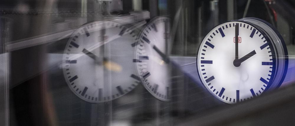 Die Uhr auf einem Gleis im Berliner Hauptbahnhof zeigt 2 Uhr in der Früh und spiegelt sich in den Glasscheiben einer Rolltreppe.