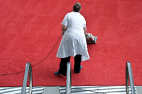 Eine Reinigungskraft saugt einen Teppich. Foto: Victoria Bonn-Meuser / DPA