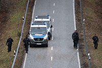 Polizeibeamte stehen an einer Absperrung an der Kreisstraße 22 rund einen Kilometer vom Tatort entfernt. Foto: Sebastian Gollnow/dpa