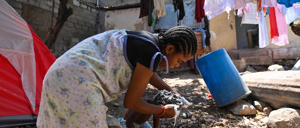 A woman washes a child at a makeshift refugee camp set up by people escaping gang activity in the Delmas 19 commune in Port-au-Prince, Haiti, on March 23, 2023, as gangs take over areas of Haiti. (Photo by Richard PIERRIN / AFP)