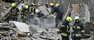 Ukrainische Rettungskräfte beseitigen nach einem russischen Raketenangriff die Trümmer von Häusern.
