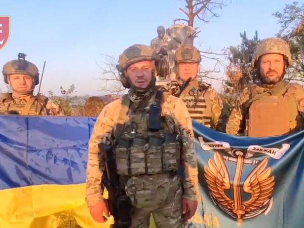 Ukrainische Marinesoldaten stehen mit der ukrainischen Flagge im angeblich befreiten Dorf Uroschajne.