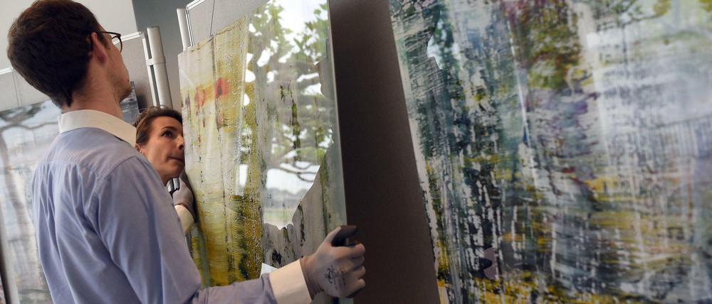 Mitarbeiter hängen Bilder von Gerhard Richter auf, die der Maler spendet, um ein Projekt gegen Wohnungslosigkeit zu unterstützen.