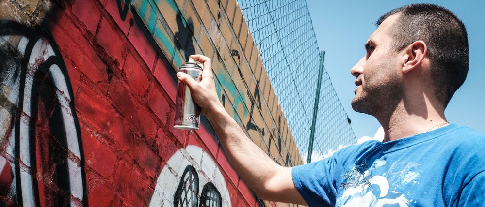 Graffiti-Künstler Ibo Omari übermalt ein Hakenkreuz-Graffiti an einer Wand in Berlin, 2016.
