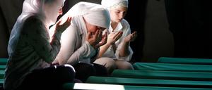Bosnische Muslimas beten  vor Särgen von Opfern des Massakers von Srebrenica, die in einer Gedenkstätte aufgestellt wurden, 2012.