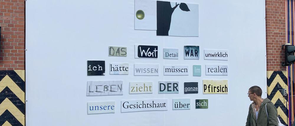 Eine Kollage aus ausgeschnittenen Wörtern von Herta Müller ist auf einem Werkstor auf dem Gelände der Uferhallen  zu sehen.  