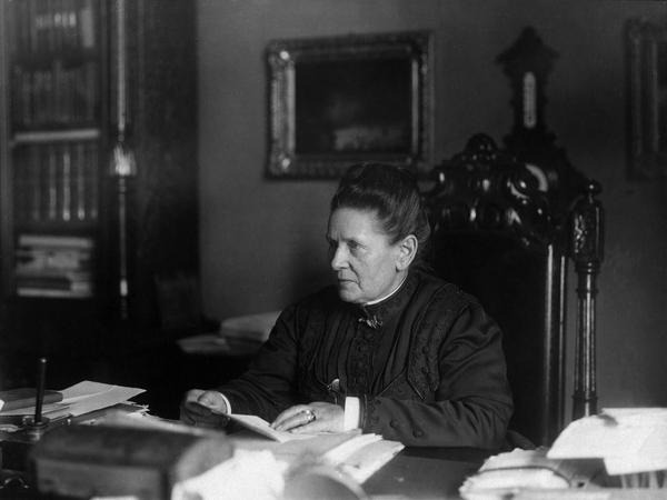Am Schreibtisch sitzend: Elvira Castner (1844 – 1923), Frauenrechtlerin, Zahnärztin und Gründerin der ersten Gartenbauschule für Frauen, in Friedenau.