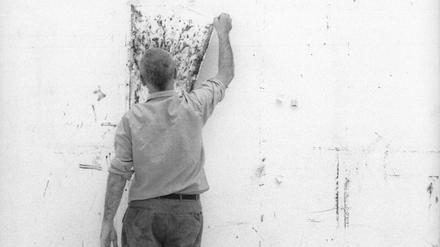 Gerhard Richter hängt ein Bild an die Wand seines Kölner Ateliers, 1990.