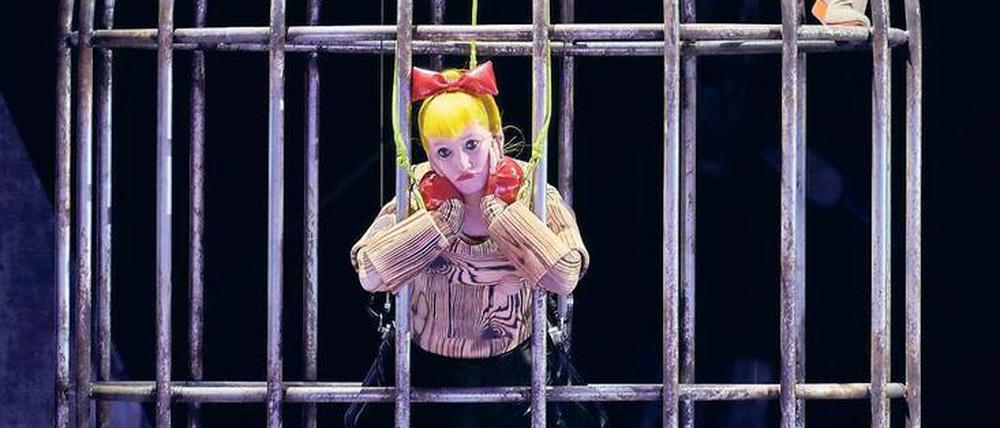 Ein Käfig voller Puppen. Sängerin Serena Saenz Molinero als Papagena und Schauspieler Florian Teichtmeister als Papageno im Bühnenbild von Mimi Lien.