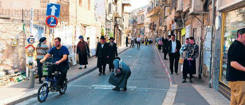 Kunst im Konflikt. Ein verärgerter orthodoxer Jude macht die von Addam Yekutieli auf die Hauptstraße des Viertels Mea Shearim gesprayte Schrift unleserlich.