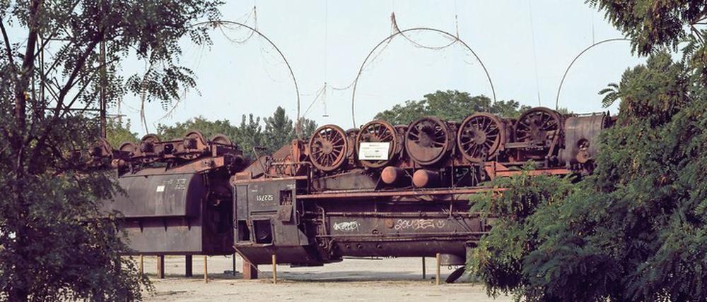 Angehaltener Bahnhof. Wolf Vostell legte anno 1987 eine Dampflok auf den Rücken – „La Tortuga“. Der Stahlbogen markierte den Umriss der großen Bahnhofshalle. 
