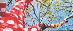Verwandlung der Welt. Im Rahmen der Ausstellung „Yayoi Kusama. Eine Retrospektive“ wurden Bäume am Gropius Bau für die Installation „Ascension of Polka Dots on Trees“ mit rotgepunkteten Bändern umwickelt.