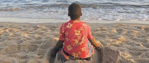 Mit den Füßen Furchen ziehen. Ein Junge am Strand von Maputo.