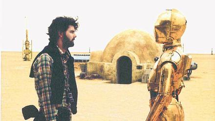 Der Regisseur und seine Erfindung. George Lucas mit dem Androiden C3PO, gespielt von Anthony Daniels, bei den Dreharbeiten zu „Krieg der Sterne“ in der tunesischen Wüste. Der Film von 1977 wurde nach den Prequels in „Episode 4“ umbenannt.