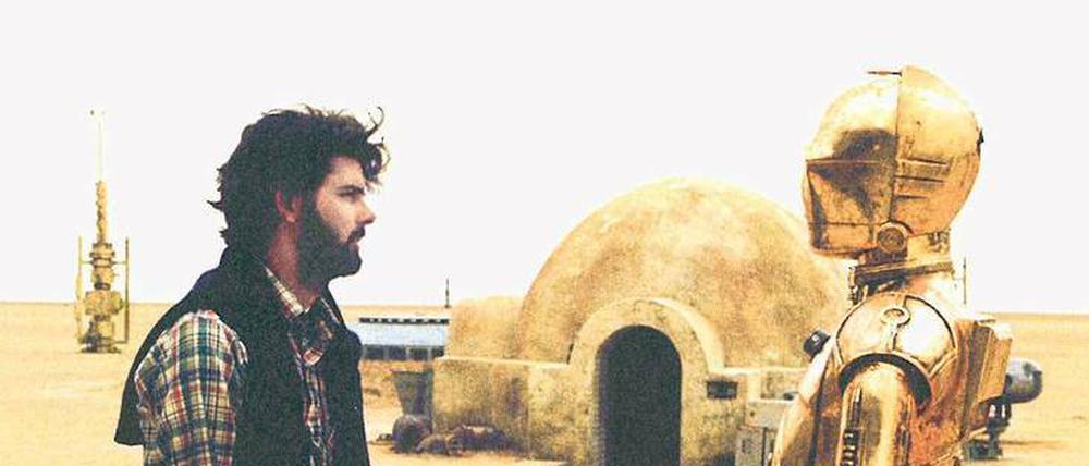 Der Regisseur und seine Erfindung. George Lucas mit dem Androiden C3PO, gespielt von Anthony Daniels, bei den Dreharbeiten zu „Krieg der Sterne“ in der tunesischen Wüste. Der Film von 1977 wurde nach den Prequels in „Episode 4“ umbenannt.