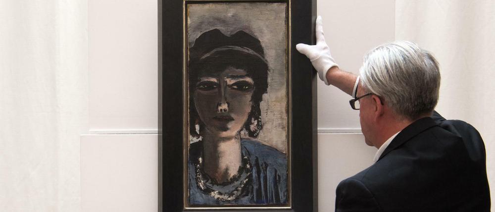 Ein Mitarbeiter der Villa Grisebach hebt das Gemälde "Die Ägypterin" von Max Beckmann vor der Versteigerung auf einen Sockel.