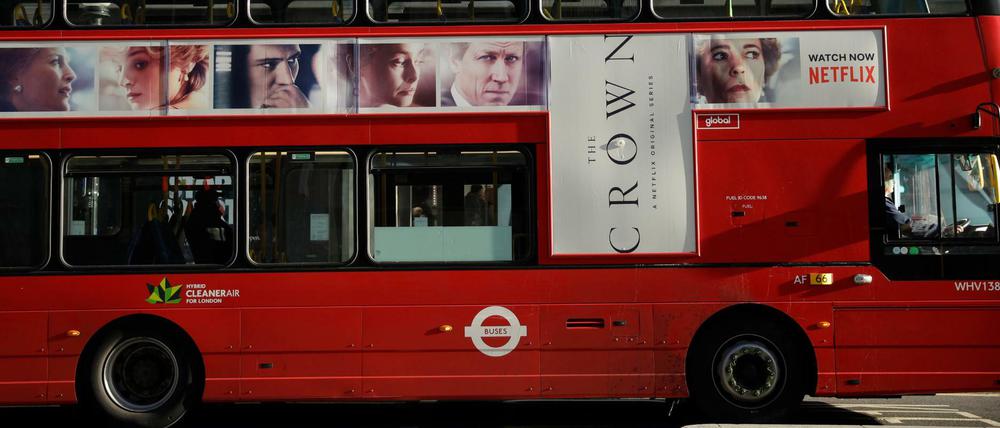 Ein traditioneller roter Doppeldeckerbus mit Werbung für die Netflix-Serie "The Crown" fährt durch das Zentrum von London. 